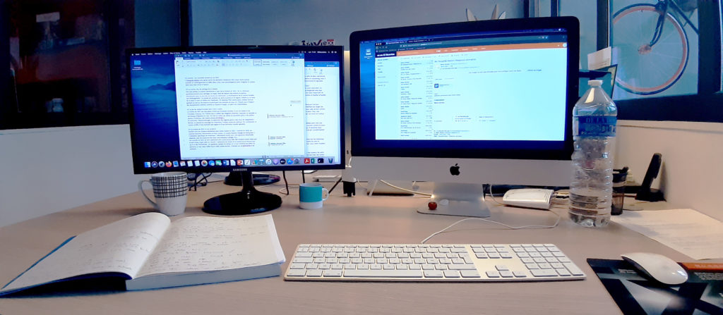 Mon bureau chez 32 Décembre : Deux écrans d'ordinateur fournis avec beaucoup d'écrits.